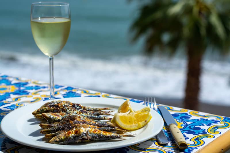 things to do in marbella in February, a tapas dish and a glass of wine served by the beach