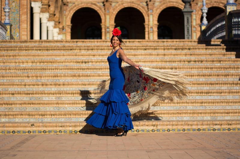 a Spanish girl with flamenco fashion clothes spinning around by the stairs