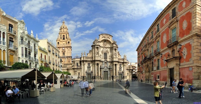 Plaza Cardenal Belluga filled with people on a sunny day in Murcia.