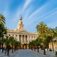 old town hall hall of Cadiz painted flesh and light yellow, blue sky and plaza surrounded by palm trees