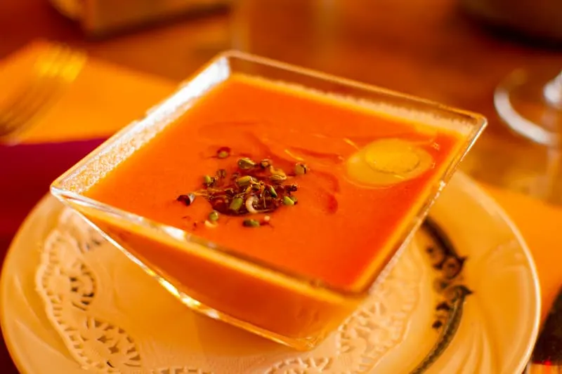 orange vegetable soup on a glass bowl on top of a plate