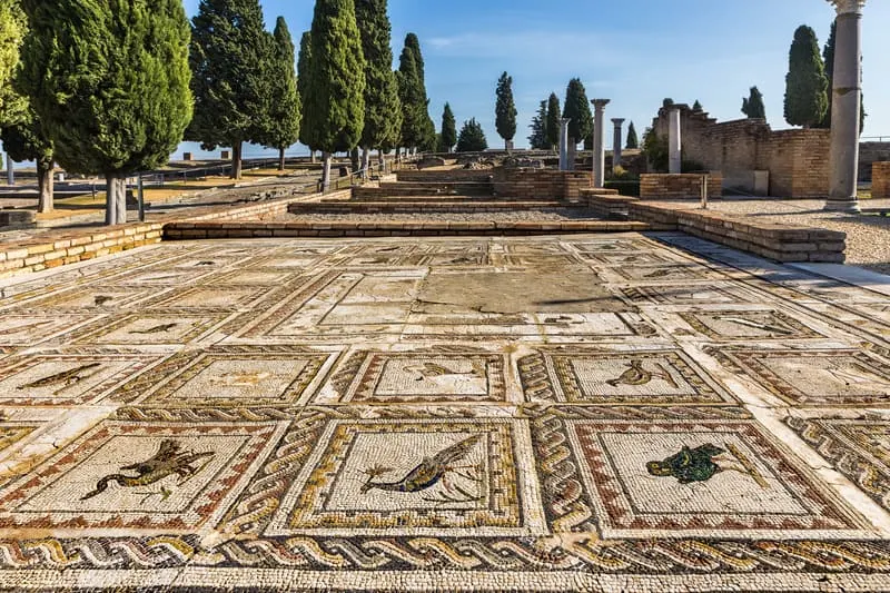 Italica with a roman mosaic on the floor in blue sky and trees on the side