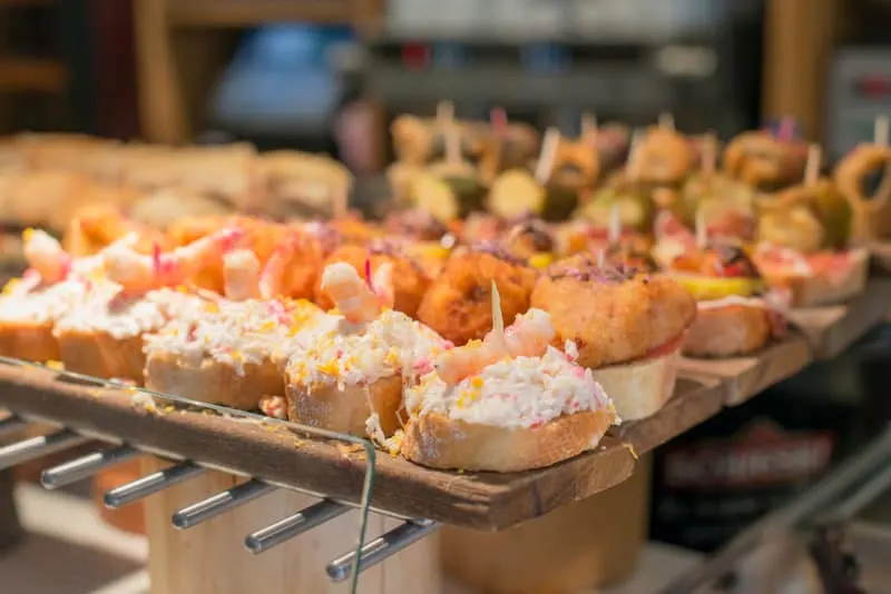 a close up of shrimpt tapa lined for display with other mix tapas displayed at the back