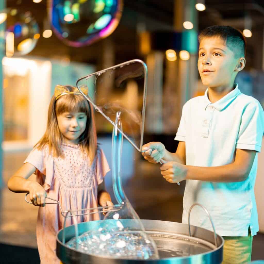 two children playing with bubbles in a museum