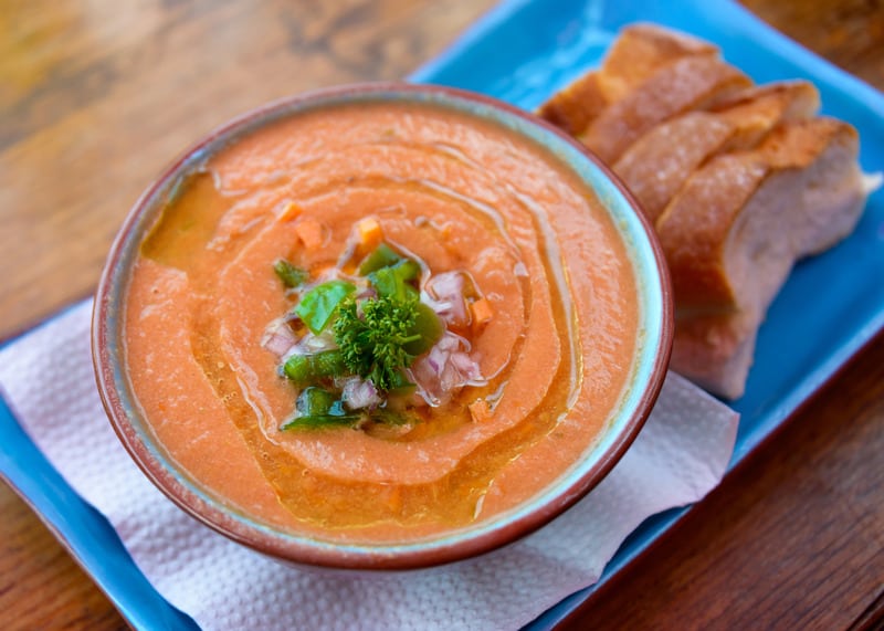 yellow tomato gazpacho in a clay bowl served with fresh bread