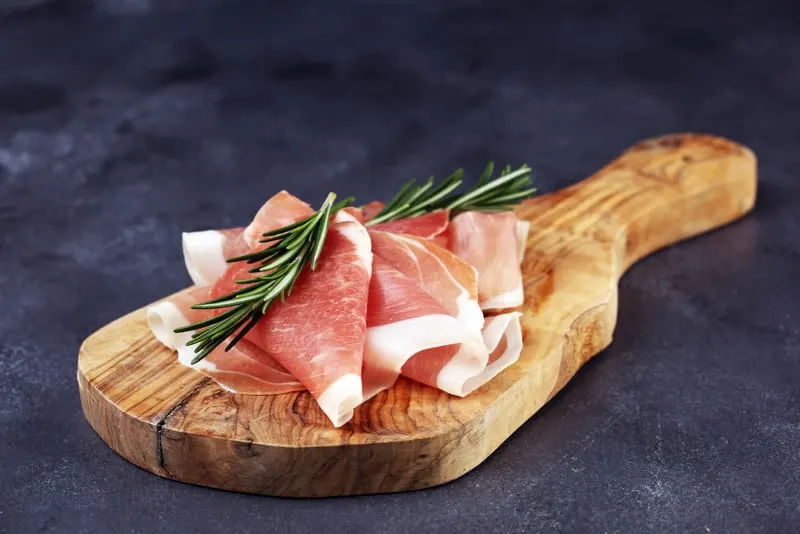 serrano ham on a cutting board for the ensalada de melon