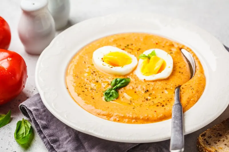 Homemade Spanish salmorejo with egg in white plate.