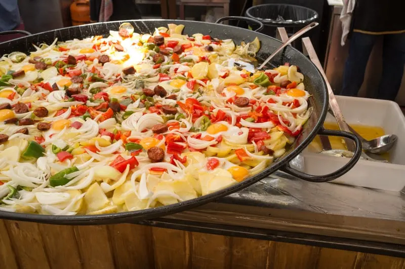 Traditional Spanish breakfast food being cooked, patatas a lo pobre in a big pan