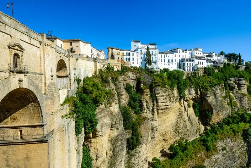 white houses on perched near a cliff with also a stone bridge nearby