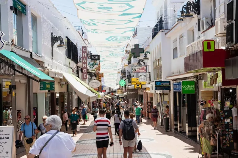 Shopper and tourists are walking along most popular street in old town named Calle San Miguel in Torremolinos. people walking on street in Southern Spain in Winter