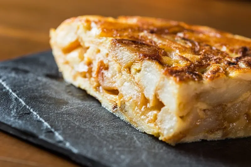 closeup with tortilla de patats on a black plate for the best spanish breakfast foods.