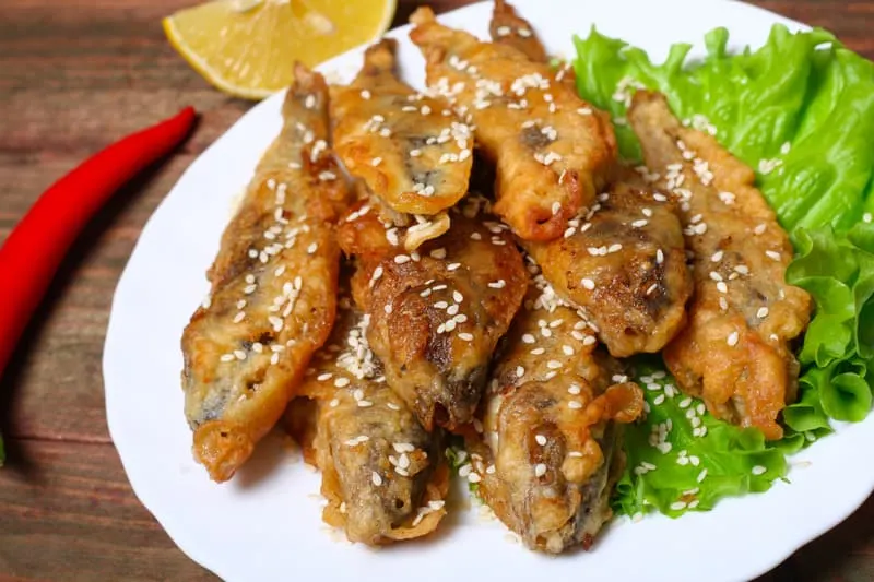 closeup of a plate with spanish boquerones fritos, battered and fried anchovies typical in Spain, on a rustic wooden table