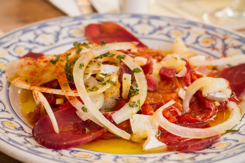 close up of sliced tuna with onions and garnish on top