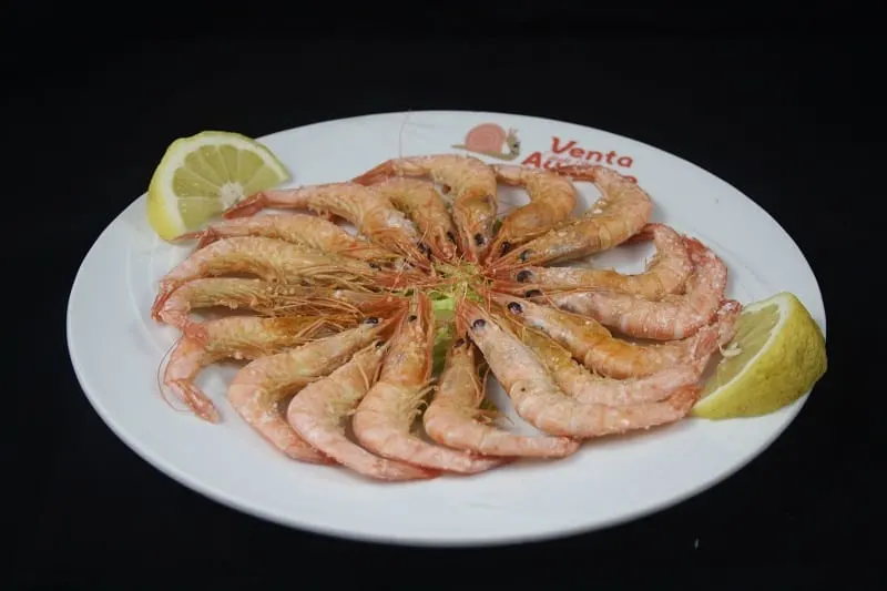 shrimps on circling on a plate with lemons slicces on the side