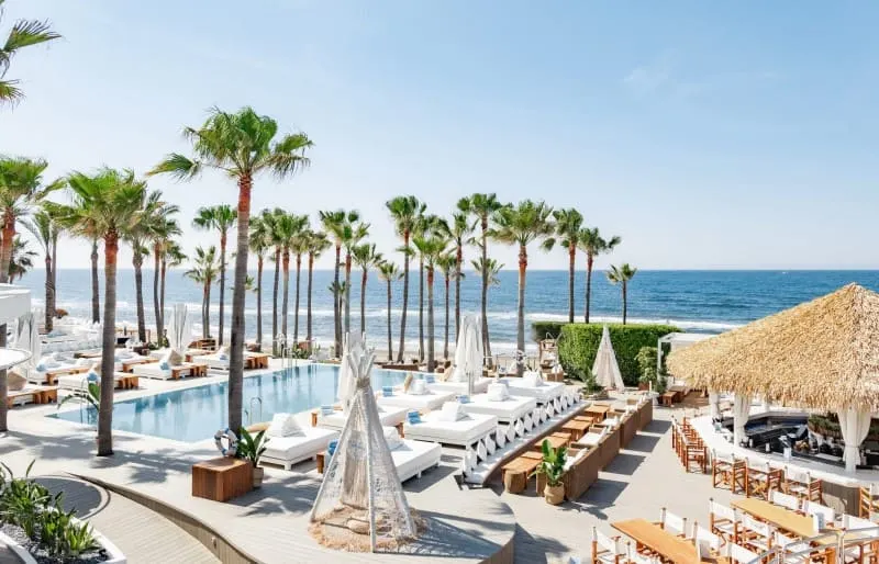Nikki Beach in Marbella with palm trees and sun lounges where the red party is held in Malaga 