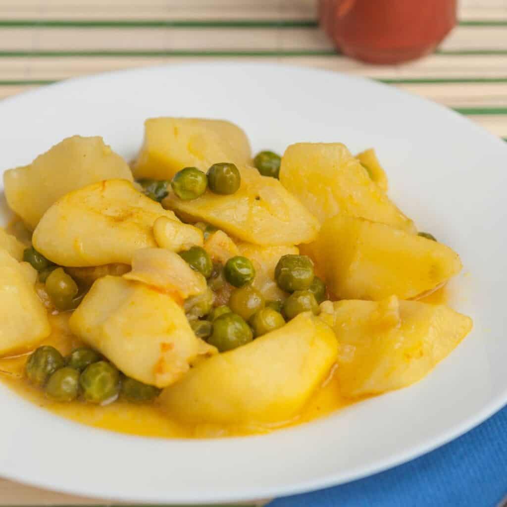 a white plate topped with potatoes and peas