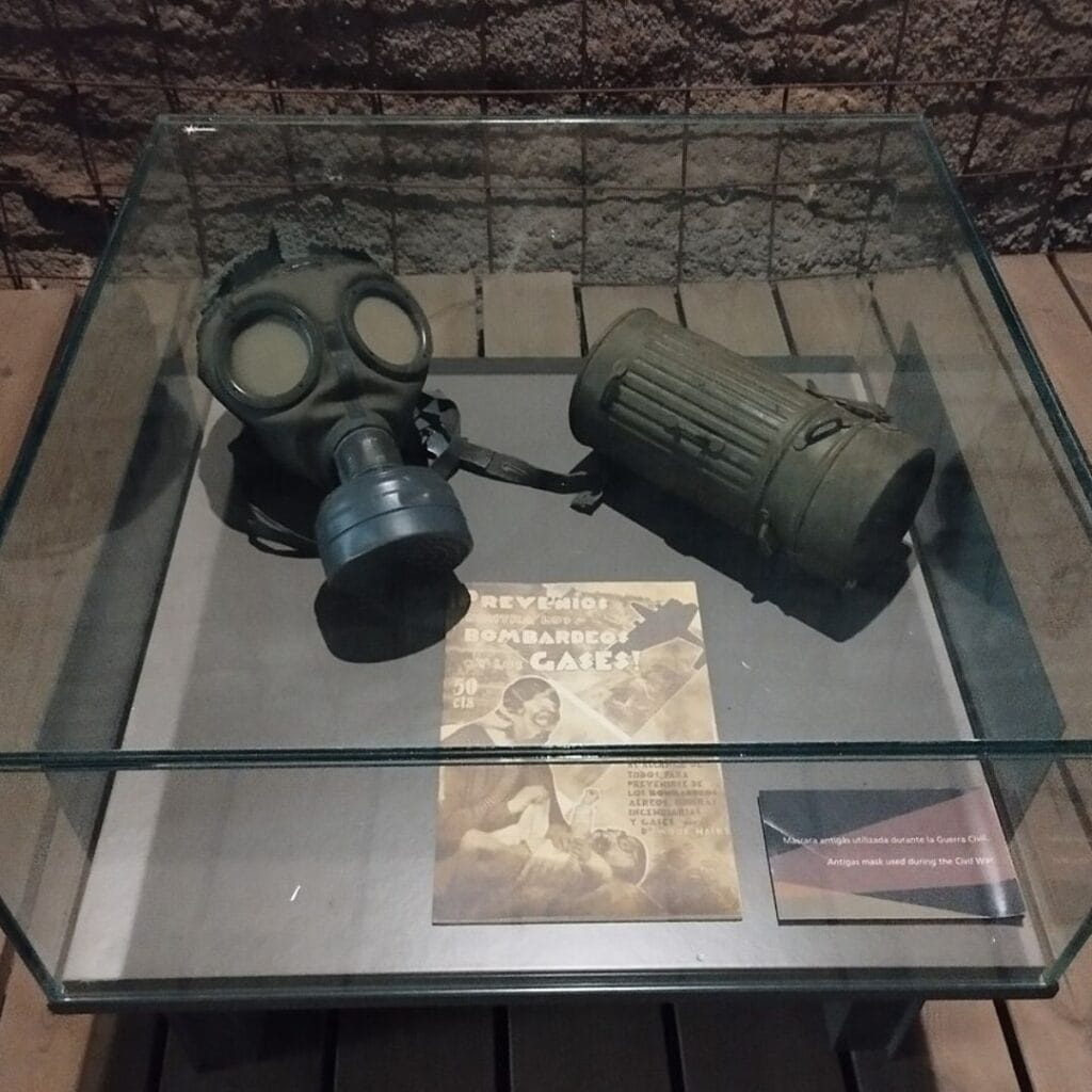 two gas masks and a book on display in a glass case