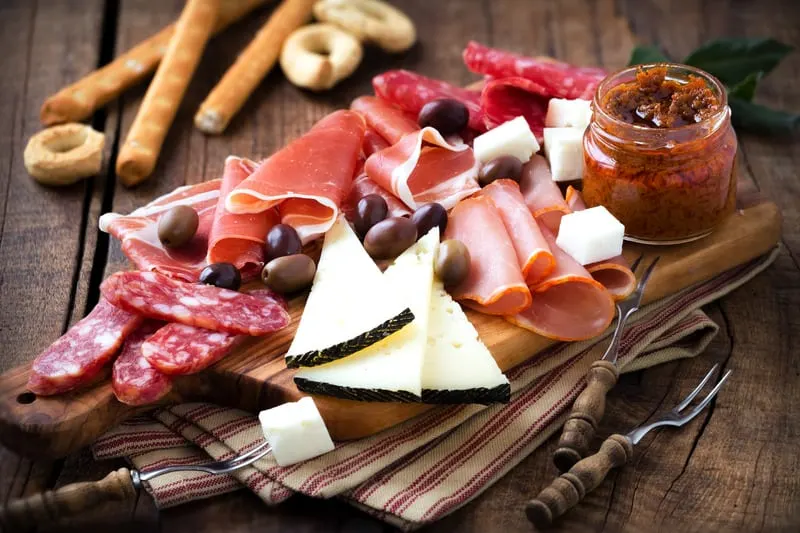 spanish jamon and cheese platter on a wooden table.