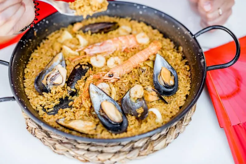 Pan with sea Paella, Valencian rice dish, on the white table outdoors