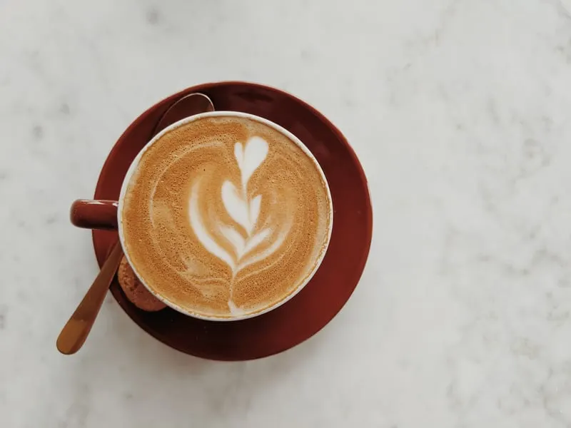 red cup of coffee on a tile with a drawing on top