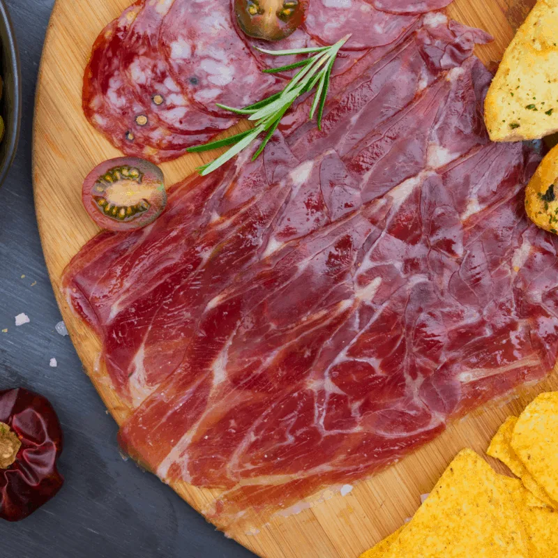 a close up of spanish ham, jamon iberico on a yellow cutting board