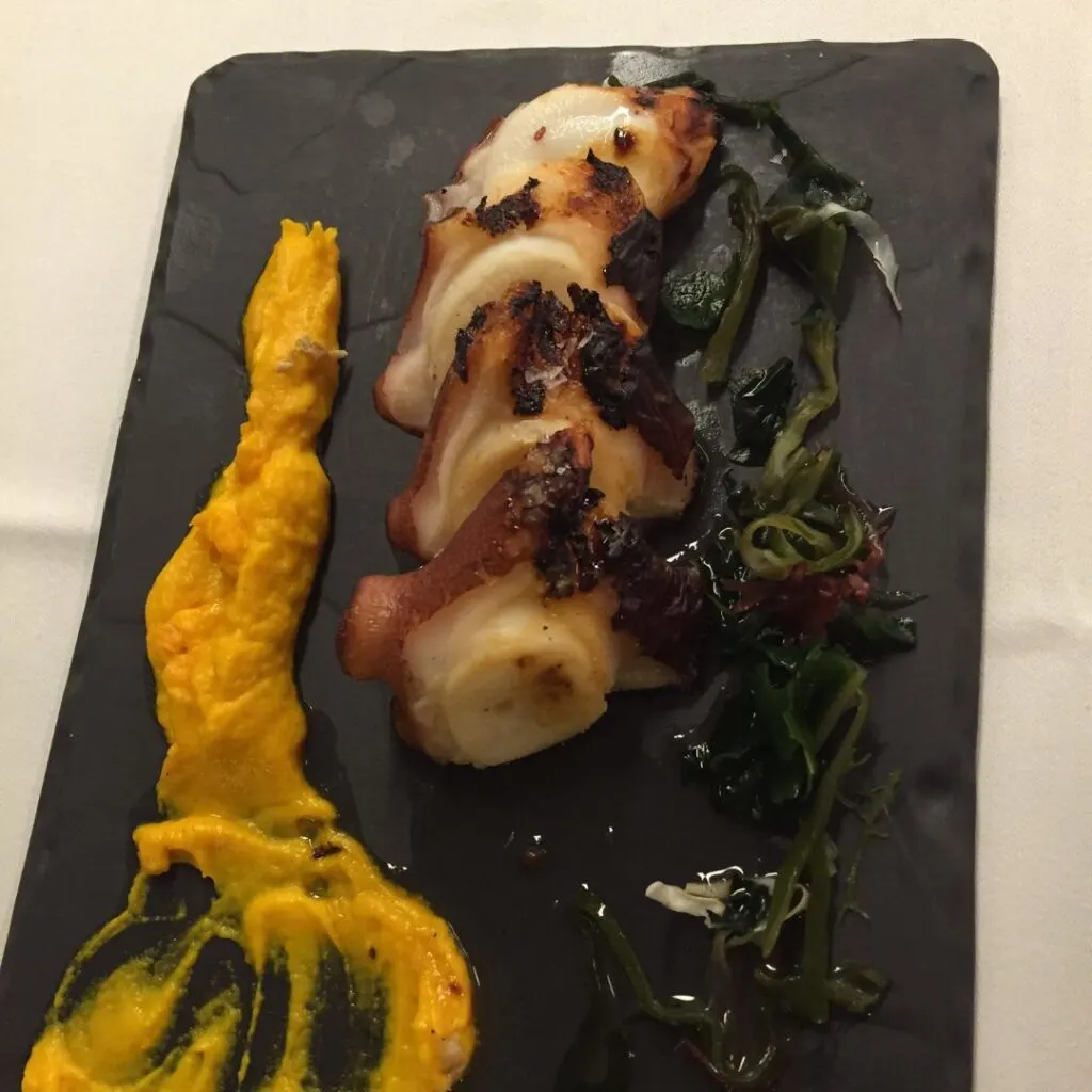 a black plate with squid and yellow sauce on it
