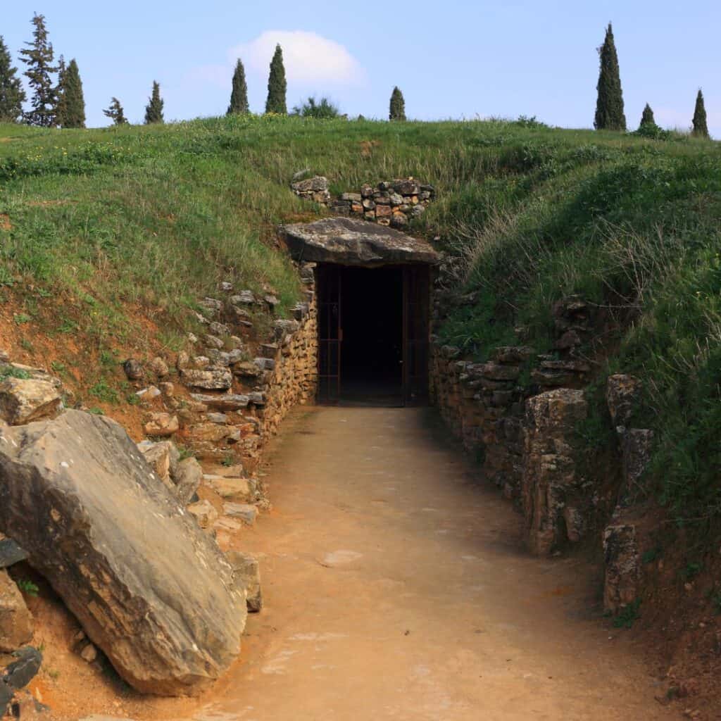 entrance to Megalithic Dolmen of Menga dating back to 5400 and 4700 BC. Small door-like opening like a burrow surrounded by rocks and greenery