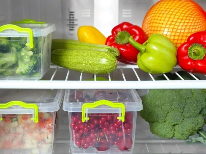 How to Store Corn Gazpacho. An open fridge with various vegetables and fruits in plastic containers.