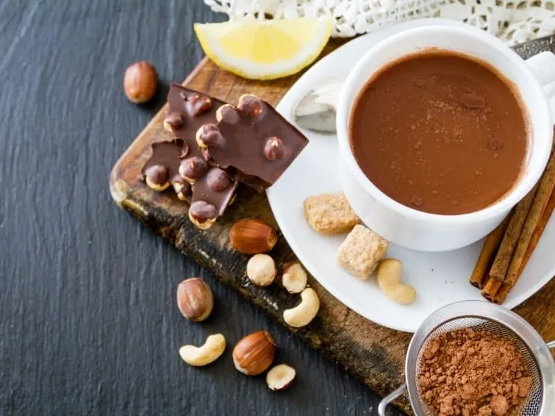 table top view, Spanish hot thick chocolate on a white cup and saucer, with chocolates and nuts