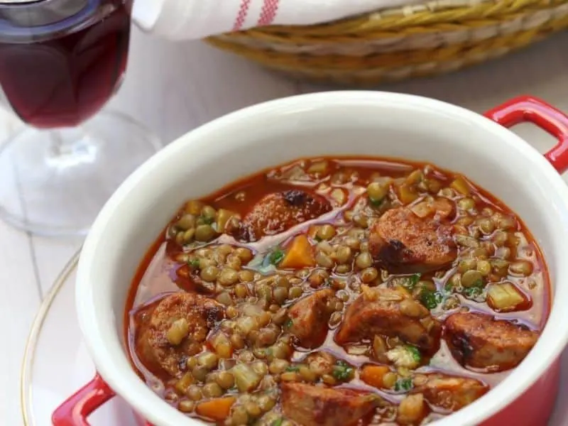 spanish lentil soup with chorizo served in a white bowl