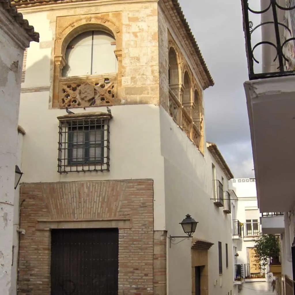 a white building with brow accents on a narrow street