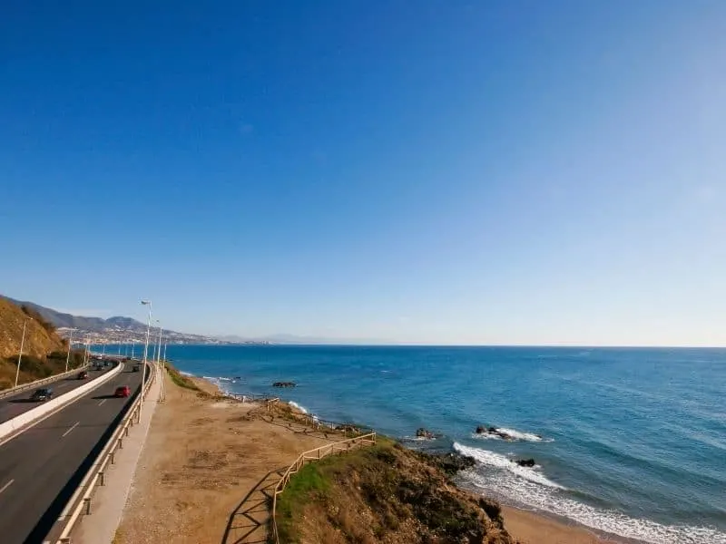 a view of spain coastal highway driving near a sea under a bright blue sky