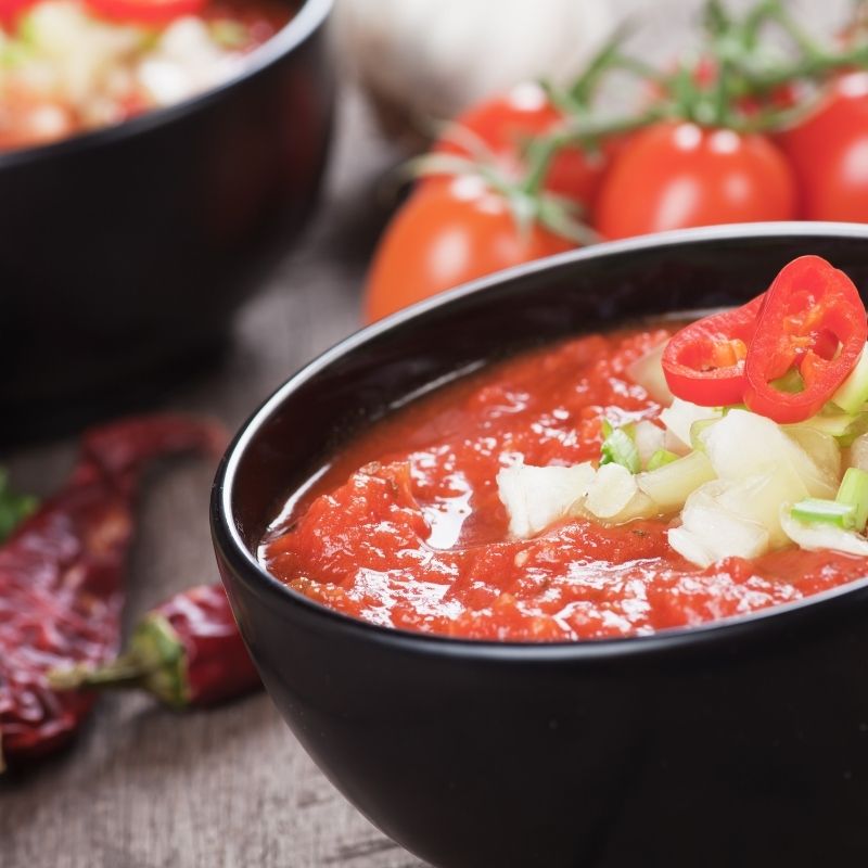 closeup with roasted tomato gazpacho in a black bowl