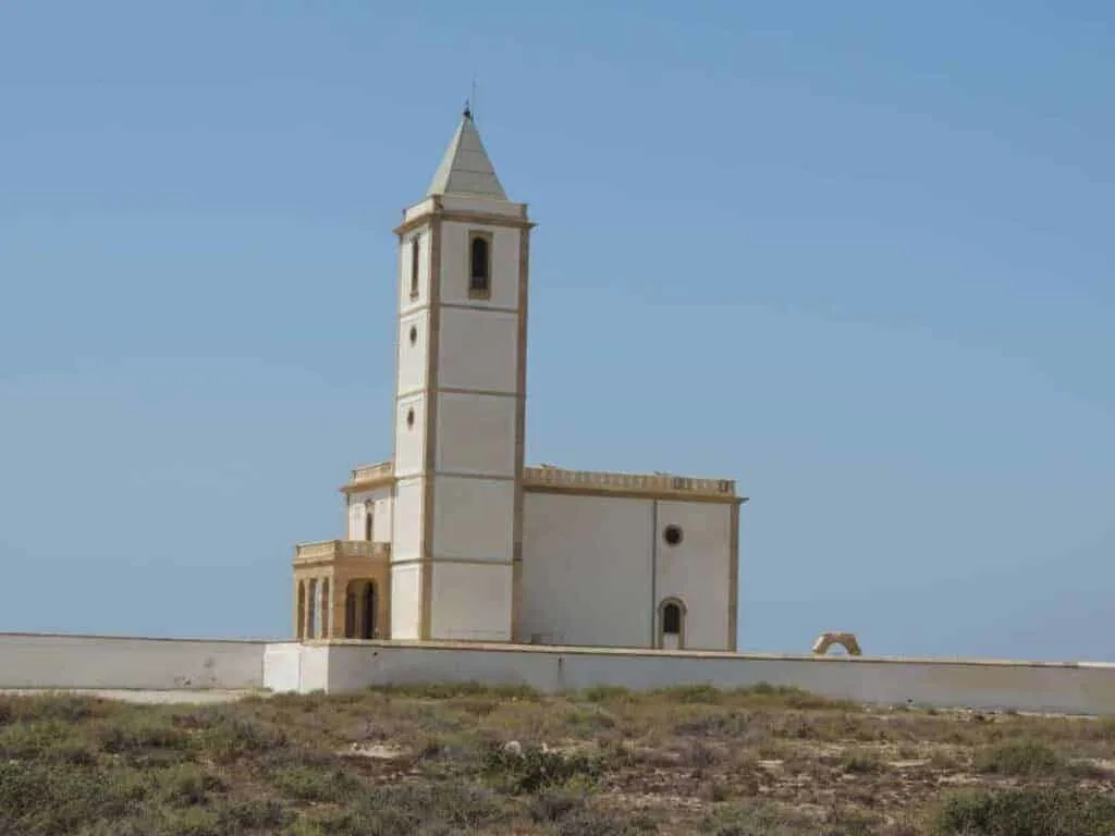 a white with yellow accents chapel on a beach