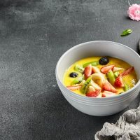 gazpacho de mango in a white bowl decorated with fruits