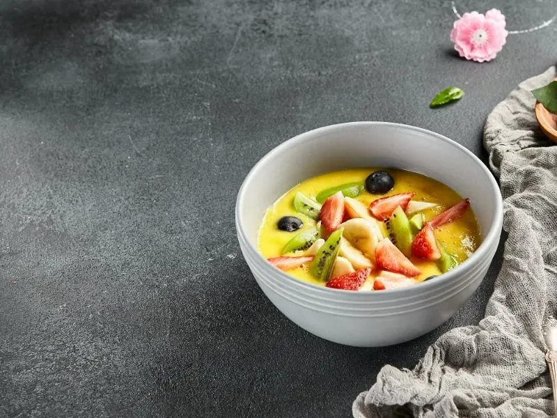 gazpacho de mango in a white bowl decorated with fruits