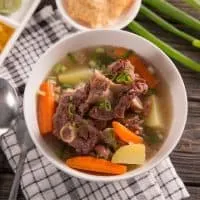 oxtail soup with vegetables in a white bowl that uses the oxtail bone broth recipe