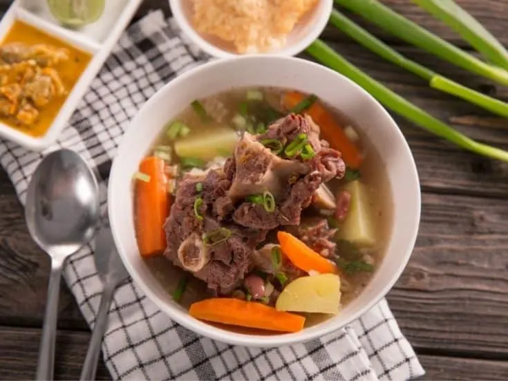 oxtail soup with mixed vegetables in a white bowl