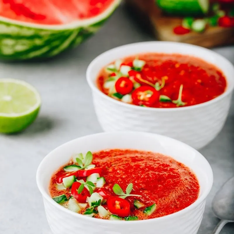Gazpacho without tomatoes in 2 bowls with a watermelon in the background.