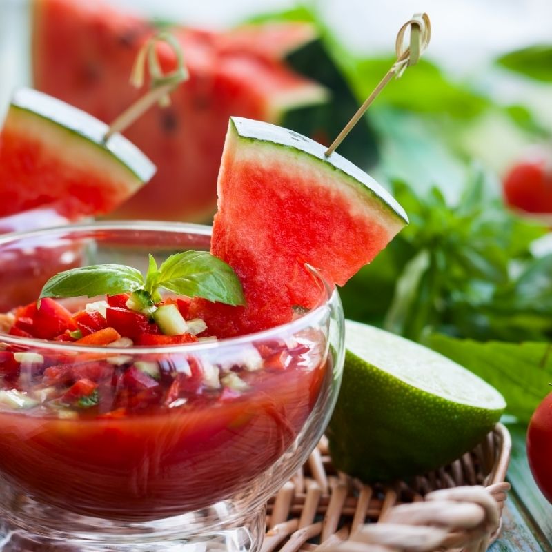 watermelon tomato Gazpacho in a glass bowl decorated with watermelon
