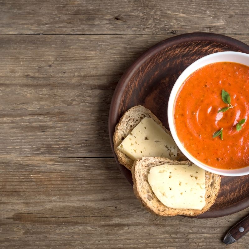 tomato leek soup in a bowl on a wooden table served with toast