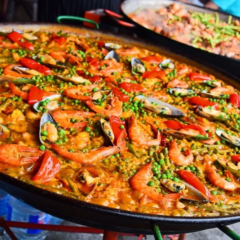 spanish valencian paella recipe filled with prawns and peas in a traditional pan