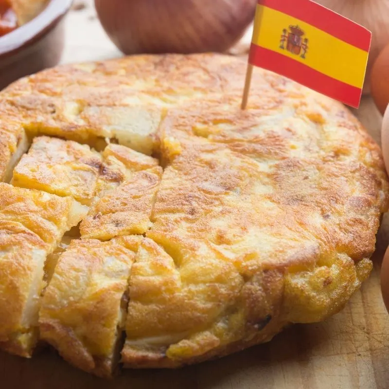 spanish tortilla with a spanish flag on top of it on a wooden table.