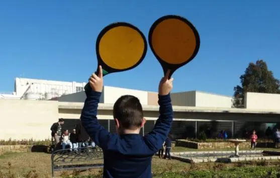 a boy holding up a  a yellow and red sign and a white building on the back at the airport museum