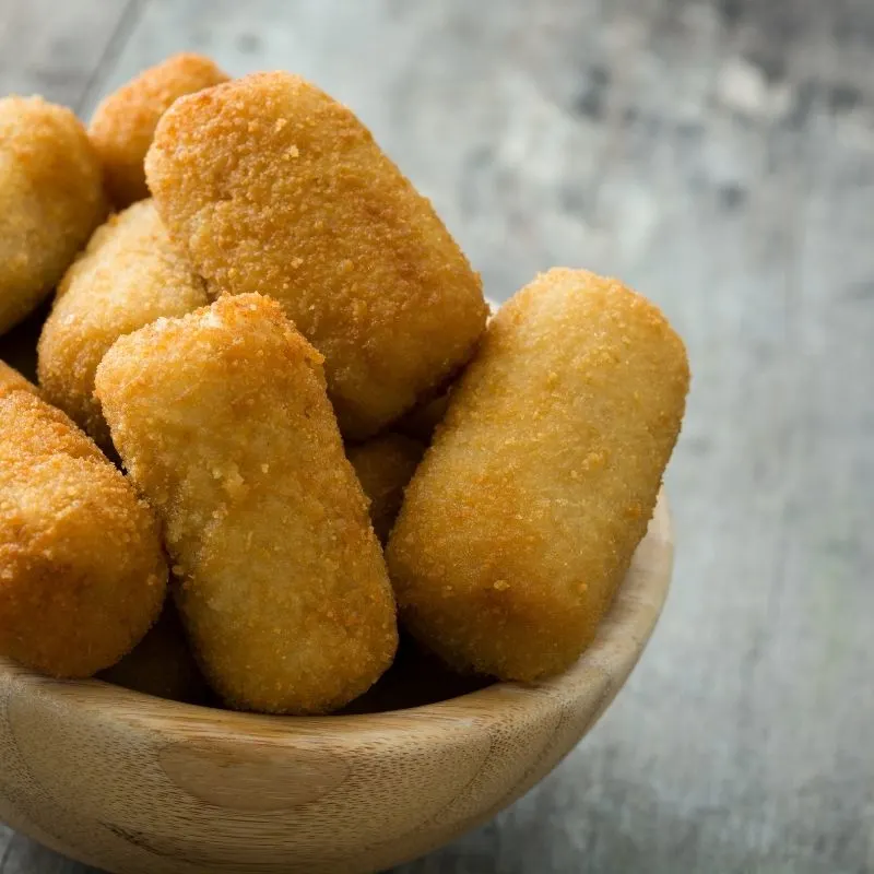 spanish croquettes recipe on a black plate, on a wooden table.