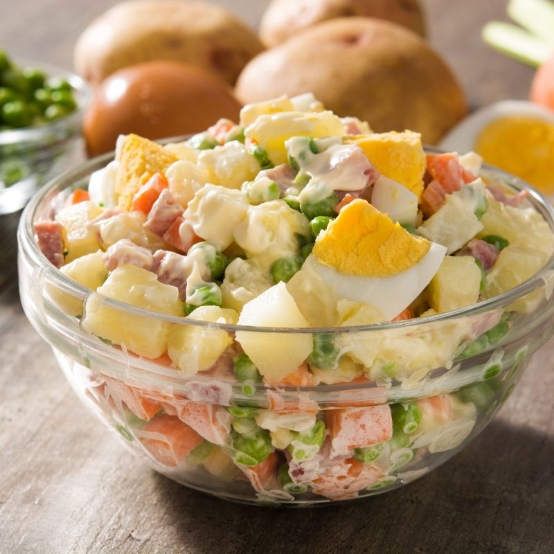 spanish potato salad with tuna and eggs  in a glass bowl