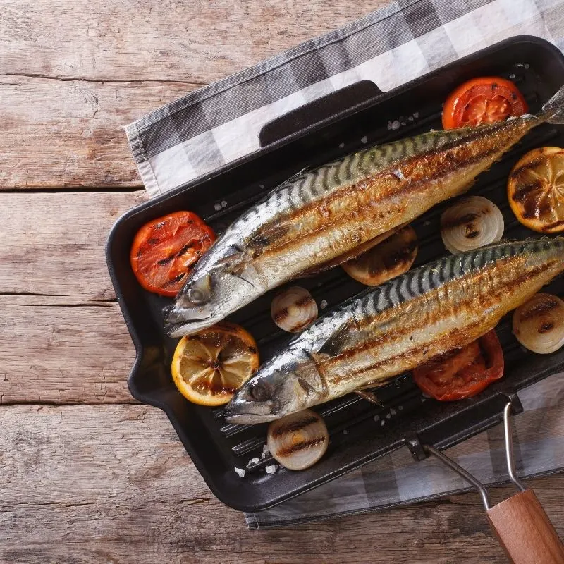 pan-fried mackerel recipe in a pan on tomatoes and lemons. 