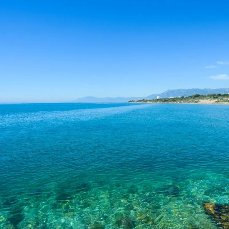 Cabopino beach, Marbella with rocks and blue water and an island far away