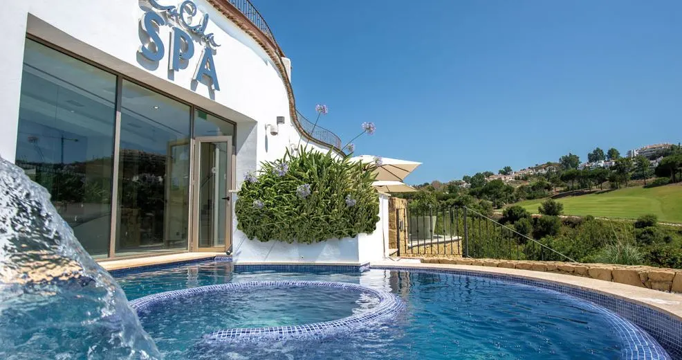 a small pool outside by a facade of La Cala Spa, Mijas overlooking trees and grass