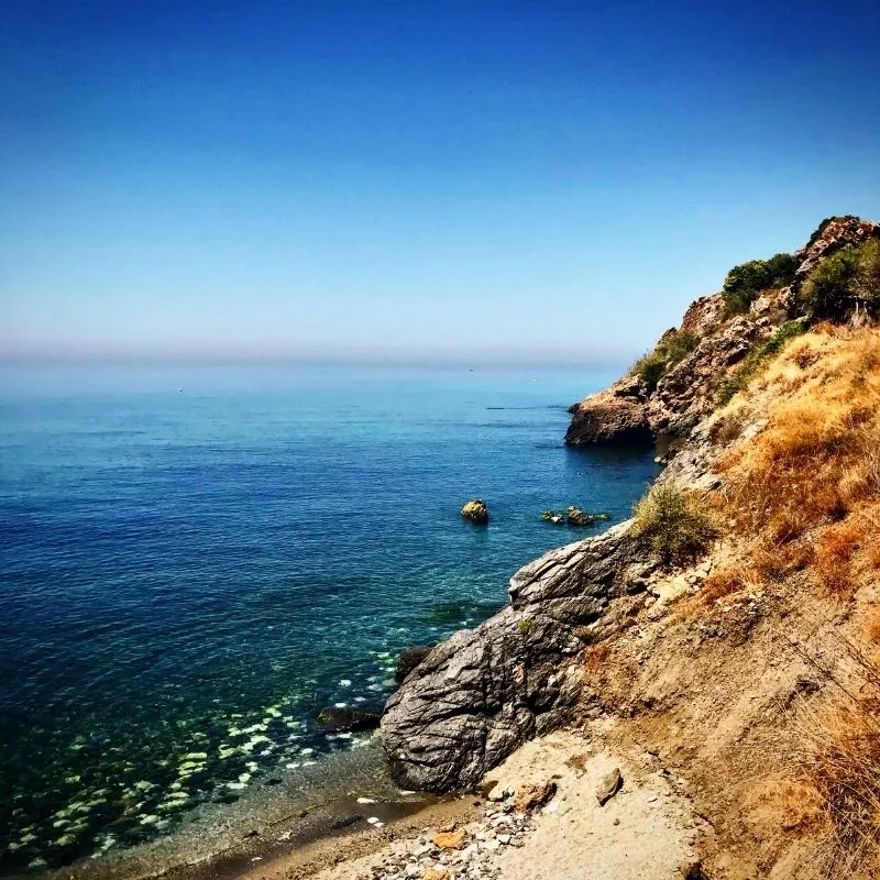 a mountain cliff and side by the beach